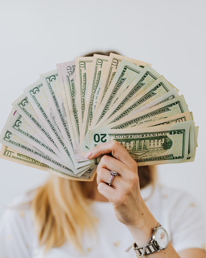 Photo of a hand with fanned out money.