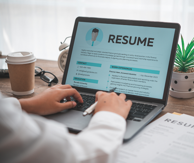 Person reviewing a résumé on a laptop at a desk.